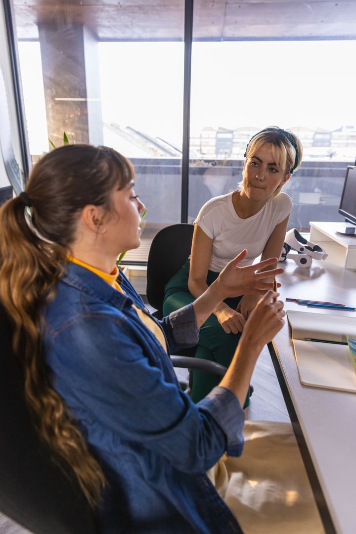 Female Colleagues Engaged in Discussion at Office Lab with Microscope