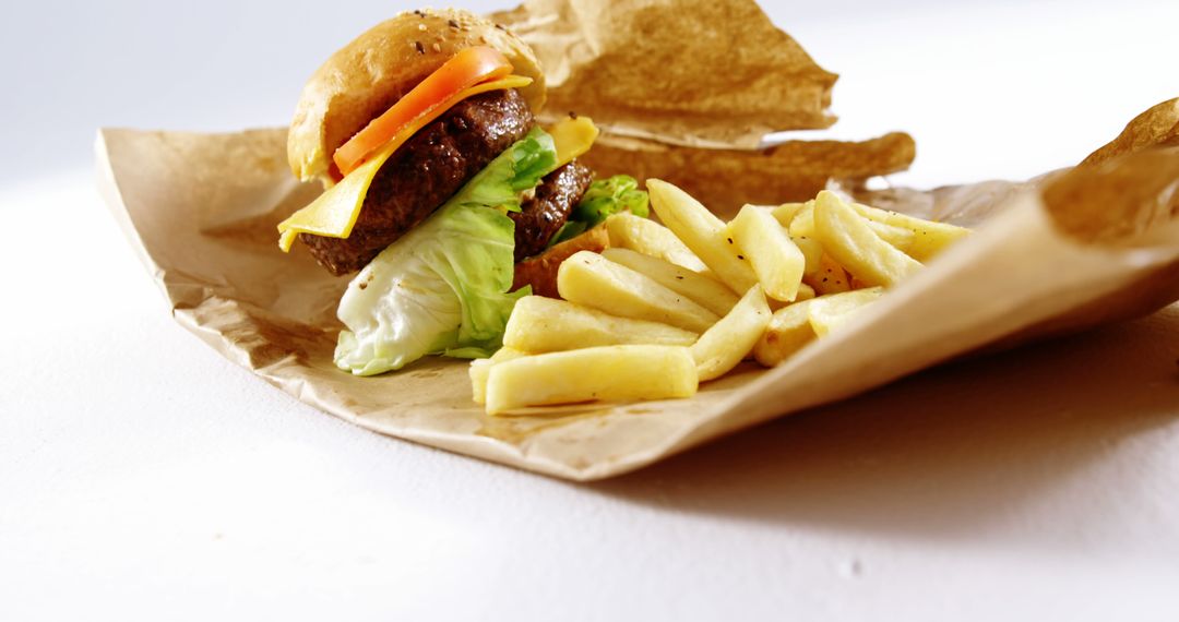 A cheeseburger is paired with a side of fries and chips, presented on a simple paper wrapping - Free Images, Stock Photos and Pictures on Pikwizard.com