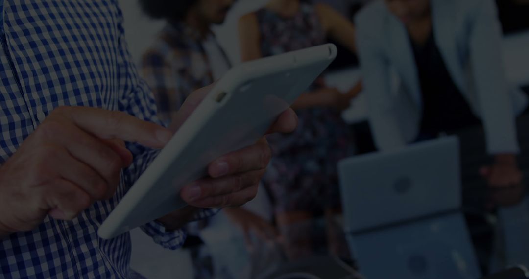 Businessman Using Tablet in Busy Corporate Meeting