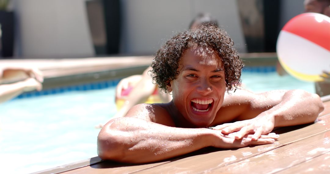 Man Laughing and Relaxing in Pool with Friends on Summer Day