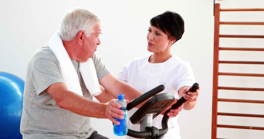 Senior Man on Exercise Bike with Physiotherapist in Rehabilitation Center - Free Images, Stock Photos and Pictures on Pikwizard.com