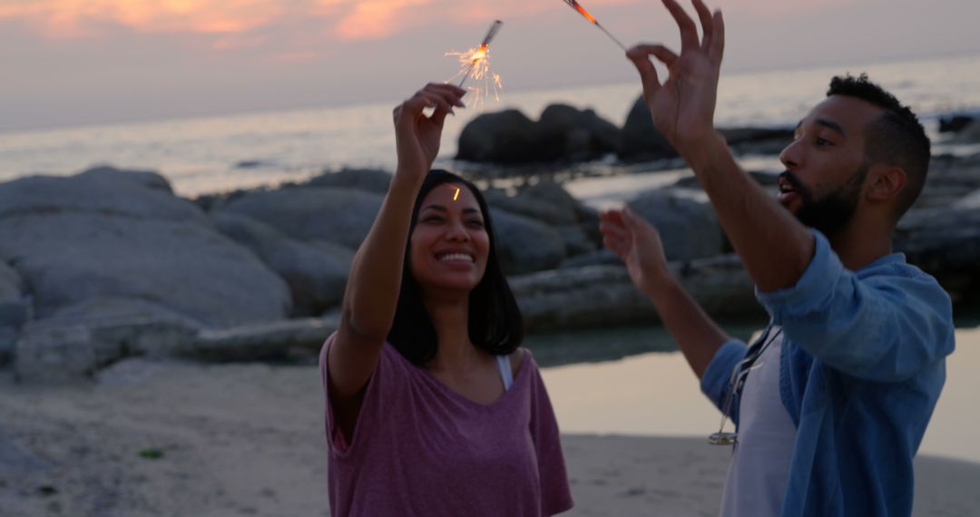 Joyful Couple Celebrating with Sparklers on Scenic Beach at Dusk - Free Images, Stock Photos and Pictures on Pikwizard.com