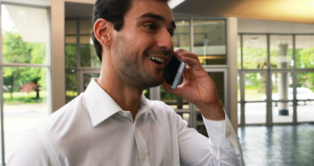 Smiling Businessman in White Shirt Talking on Smartphone at Office Entrance - Free Images, Stock Photos and Pictures on Pikwizard.com