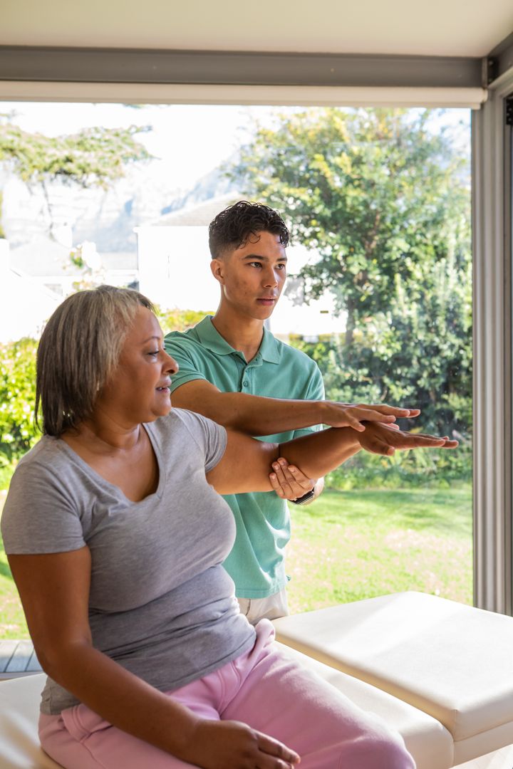 Therapist Guiding Senior in Therapeutic Stretch by Sunlit Window