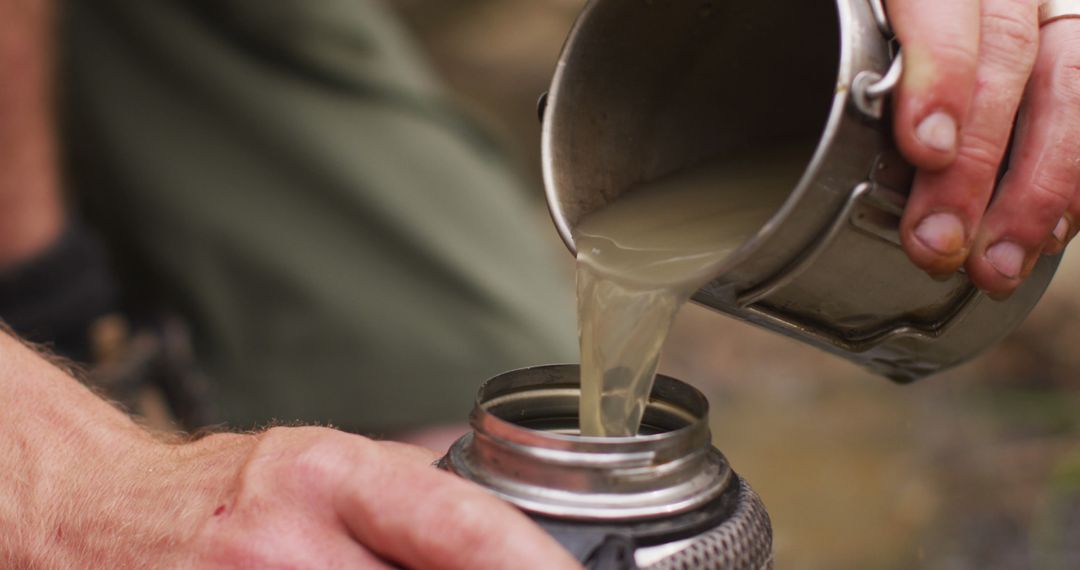 Person pouring murky water into metal flask - Free Images, Stock Photos and Pictures on Pikwizard.com