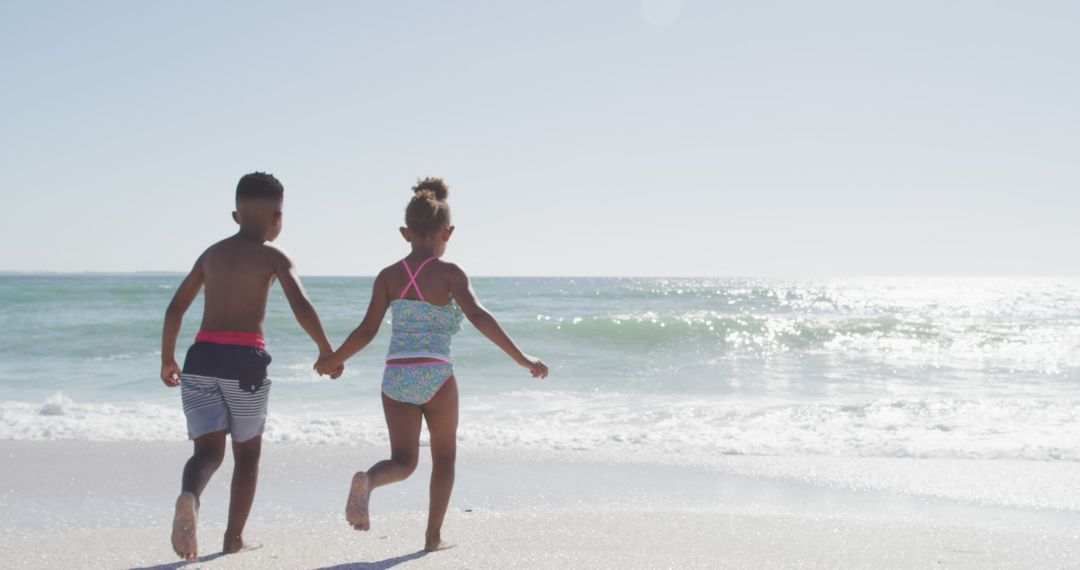 Children Running Towards Beach Waves on Sunny Day - Free Images, Stock Photos and Pictures on Pikwizard.com