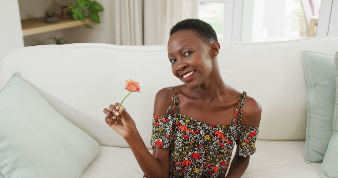 Smiling Woman Holding Flower Sitting on White Sofa at Home - Free Images, Stock Photos and Pictures on Pikwizard.com