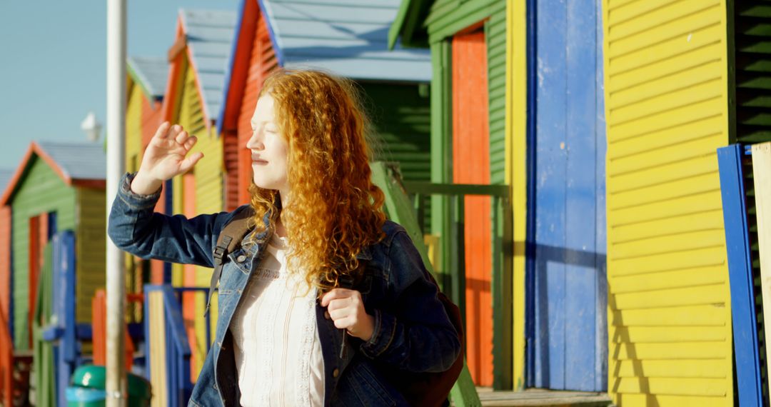 Smiling Woman Enjoying Sunny Day Outside Colorful Wooden Beach Huts - Free Images, Stock Photos and Pictures on Pikwizard.com