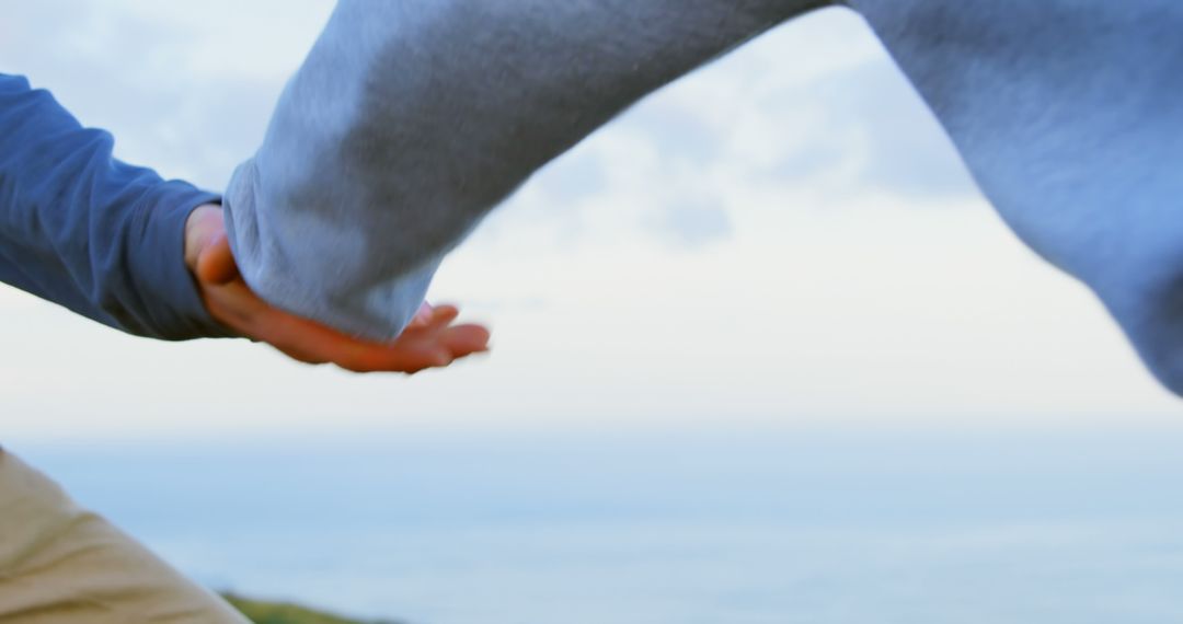 Two people are holding hands against a serene sky, with copy space - Free Images, Stock Photos and Pictures on Pikwizard.com