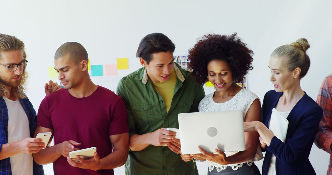 Young Adults Collaborating with Digital Devices in Modern Workspace