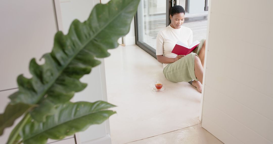 Woman Reading Book beside Window with Drink on Floor - Free Images, Stock Photos and Pictures on Pikwizard.com