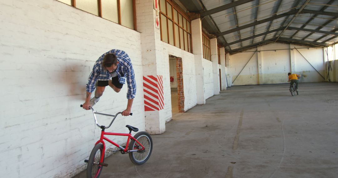 Young Man Performing BMX Trick in Industrial Warehouse - Free Images, Stock Photos and Pictures on Pikwizard.com