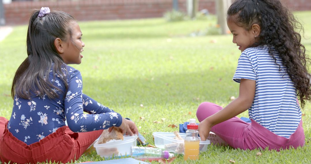 Two young girls enjoying outdoor picnic at school