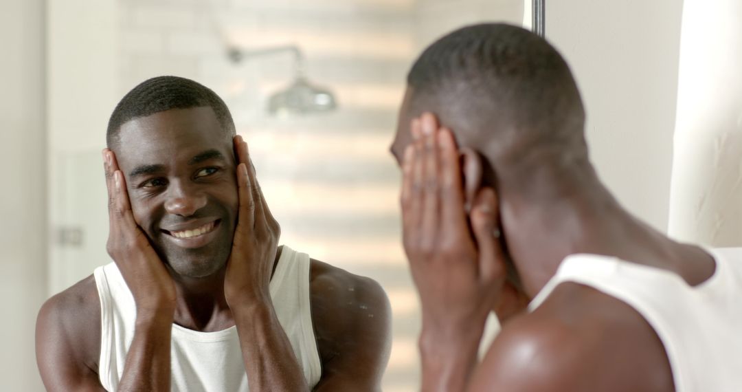 African American man smiling at mirror practicing morning grooming and skincare routine