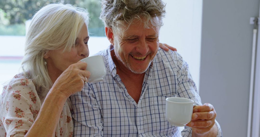 Happy elderly couple sharing coffee at home - Free Images, Stock Photos and Pictures on Pikwizard.com