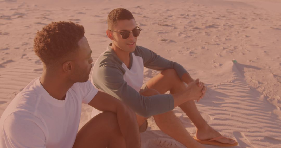 Two Friends Relaxing on Sandy Beach in Warm Sundown Glow