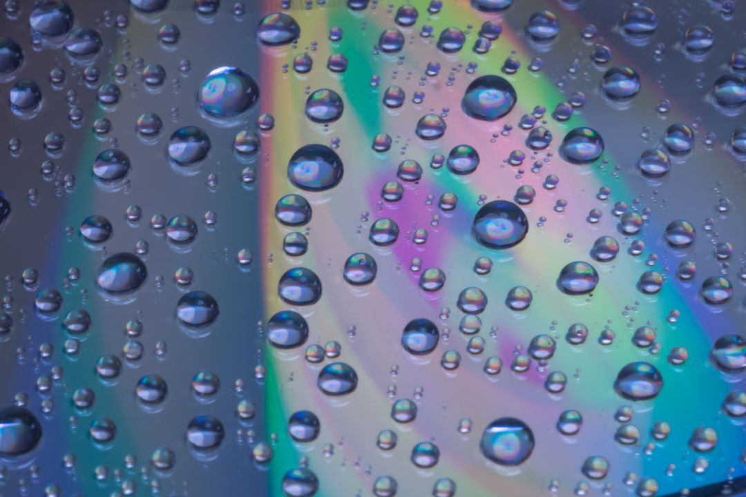 Close-Up of Water Droplets on Colorful Surface Creating Rainbow Effect - Free Images, Stock Photos and Pictures on Pikwizard.com