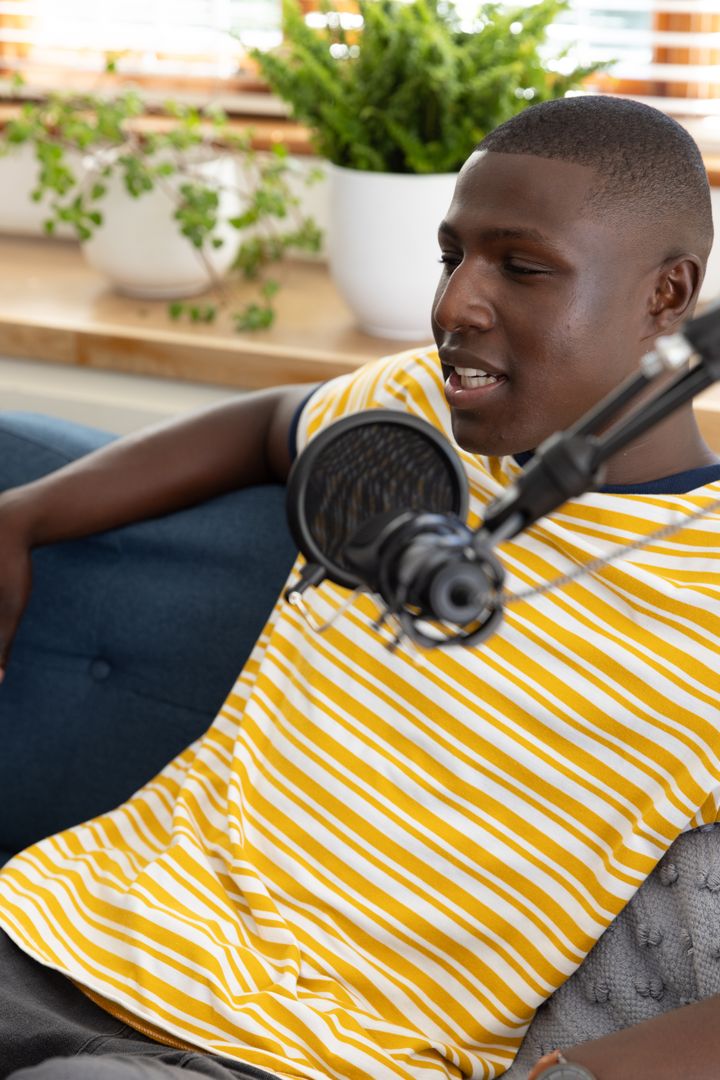 Young Male Podcaster Speaking Into Condenser Microphone at Home Studio