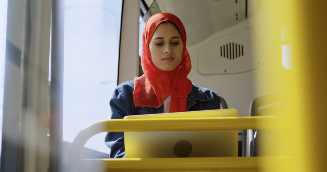 Confident Woman in Red Hijab Working on Laptop While Traveling by Bus - Free Images, Stock Photos and Pictures on Pikwizard.com