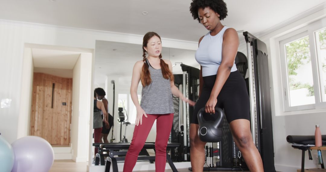 Fitness Trainer Guides Woman Through Kettlebell Exercise Routine