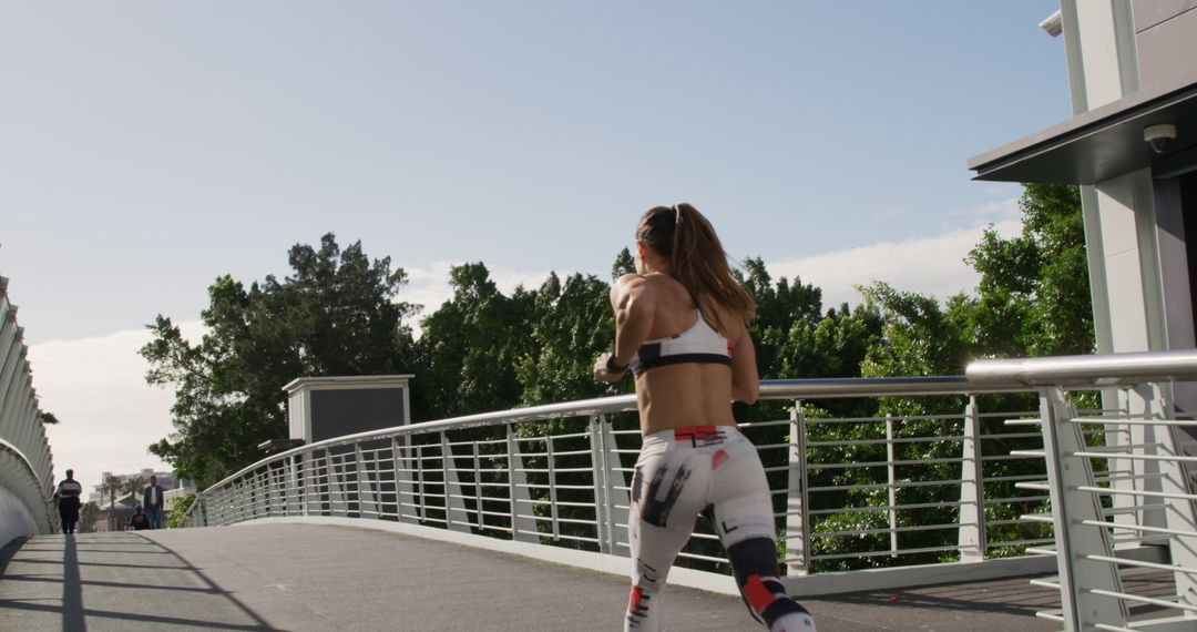 Woman Jogging on a Bridge in Athletic Wear on a Sunny Day - Free Images, Stock Photos and Pictures on Pikwizard.com