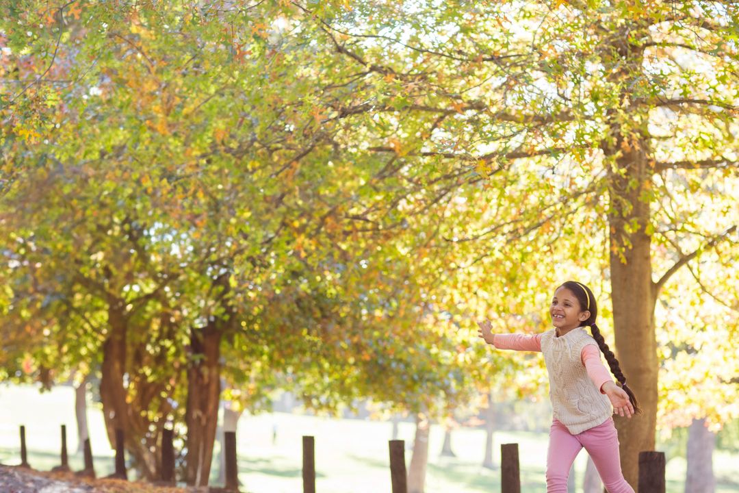 Laughing Girl Balancing in Autumn Park Under Golden Trees