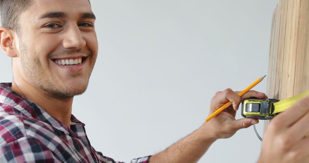 Smiling Man Measuring Wall with Tape Measure and Pencil - Free Images, Stock Photos and Pictures on Pikwizard.com