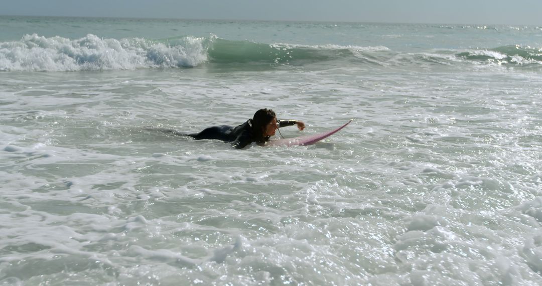 Young biracial woman catches waves at the beach, with copy space - Free Images, Stock Photos and Pictures on Pikwizard.com