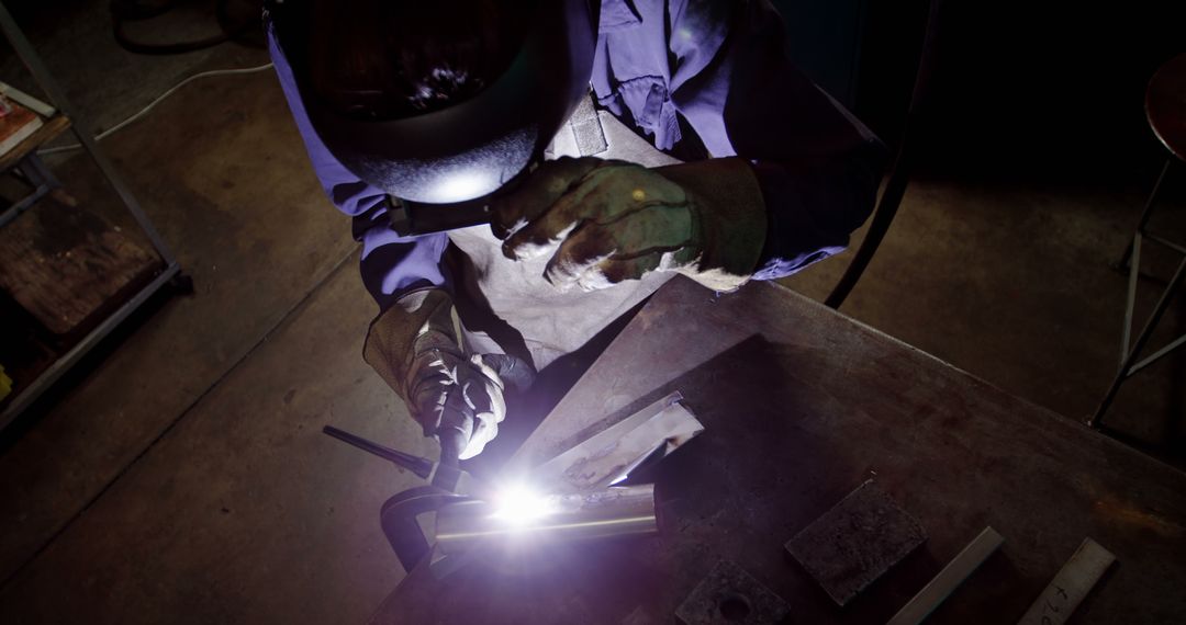 Welder Concentrating on Metalwork in Dark Workshop - Free Images, Stock Photos and Pictures on Pikwizard.com