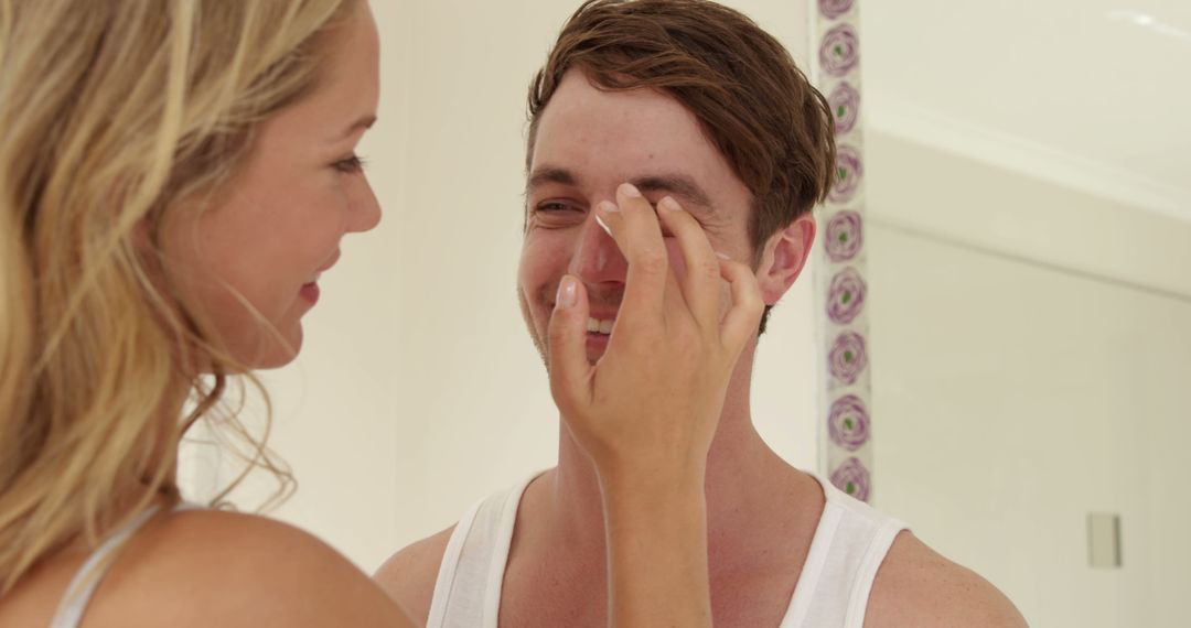 A young Caucasian woman applies cream to the face of a smiling young Caucasian man, with copy space - Free Images, Stock Photos and Pictures on Pikwizard.com