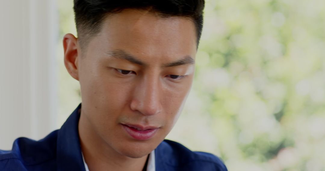 Asian Man Concentrating During Phone Call in Park Environment