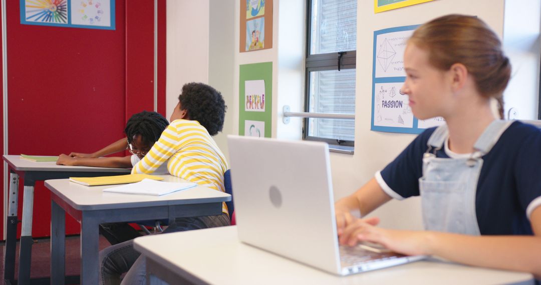 Schoolgirl Using Laptop While Classmates Engage in Discussion at School