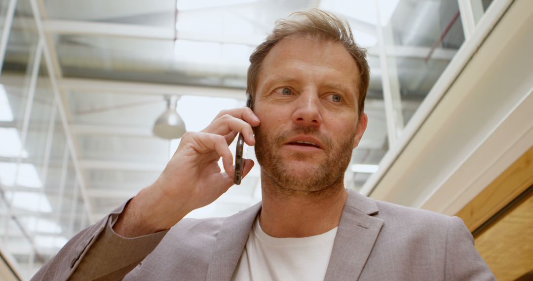 Mid-30s Businessman Talking on Phone in Modern Office Environment - Free Images, Stock Photos and Pictures on Pikwizard.com