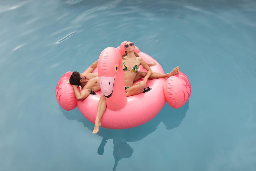 Couple Relaxing on Pink Inflatable Flamingo float in Pool - Free Images, Stock Photos and Pictures on Pikwizard.com