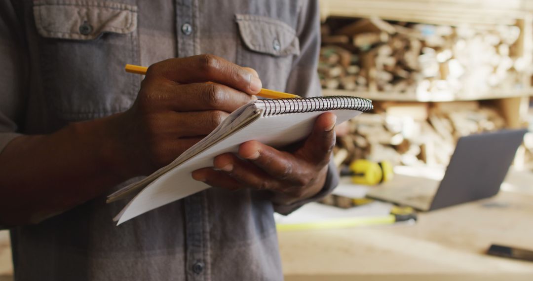 Carpenter Taking Notes in Workshop