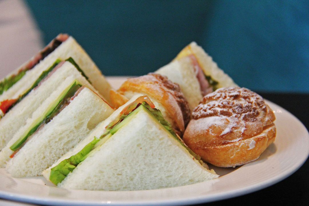 Triangle Tea Sandwiches with Fresh Lettuce and Ham Paired with Sugar-Dusted Cream Puffs
