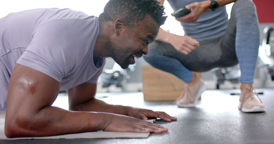 African American Man Doing Push-Ups With Trainer Guidance at Gym