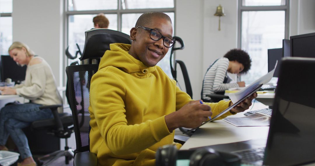 Smiling Creative Businessman Reviewing Documents in Modern Office