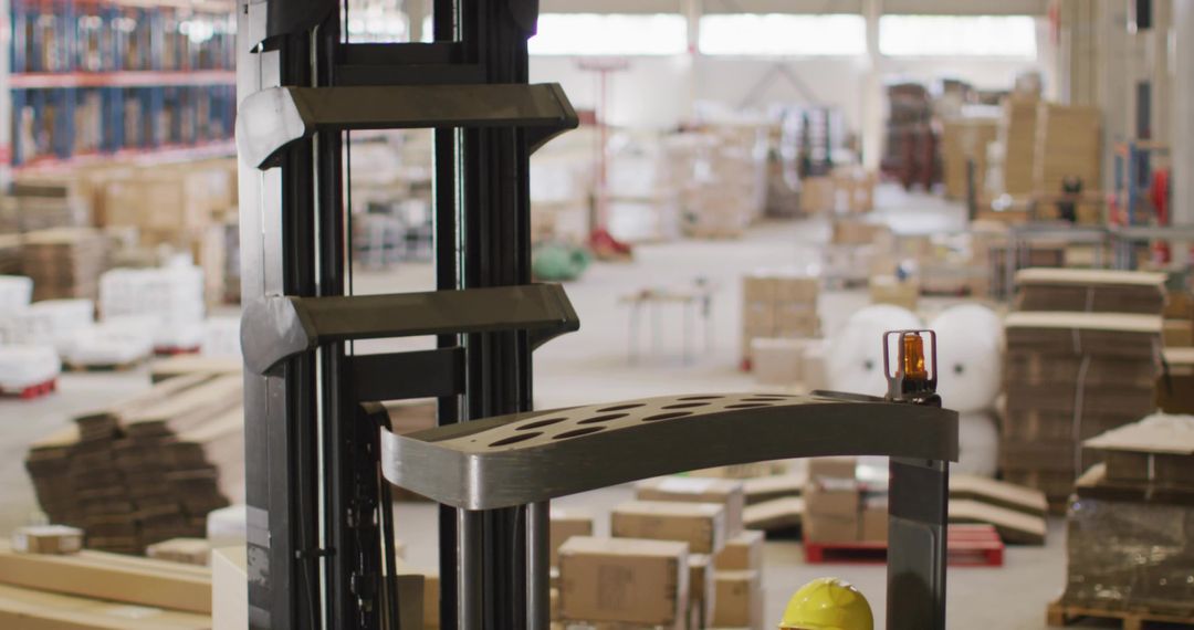 Forklift mast with amber beacon and worker inspecting pallets in warehouse logistics hub