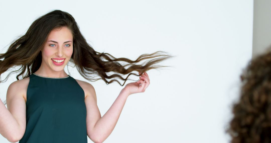 A young Caucasian woman is playfully twirling her long brown hair, with copy space - Free Images, Stock Photos and Pictures on Pikwizard.com