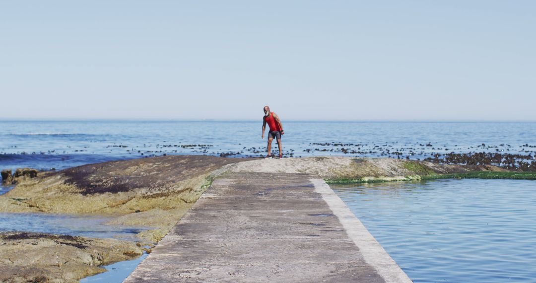 Man exploring rocky coastline near ocean under clear sky - Free Images, Stock Photos and Pictures on Pikwizard.com