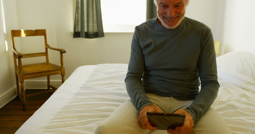 Elderly man using tablet on bed in bright bedroom - Free Images, Stock Photos and Pictures on Pikwizard.com