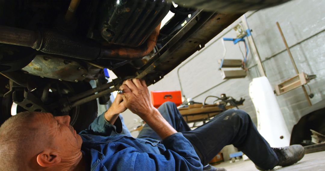 Mechanic Repairing Car Engine Underneath in Workshop - Free Images, Stock Photos and Pictures on Pikwizard.com