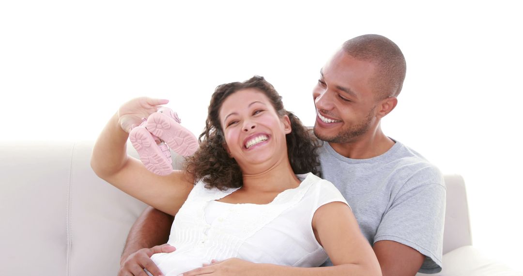 Expectant Couple Smiling and Holding Pink Baby Shoes - Free Images, Stock Photos and Pictures on Pikwizard.com