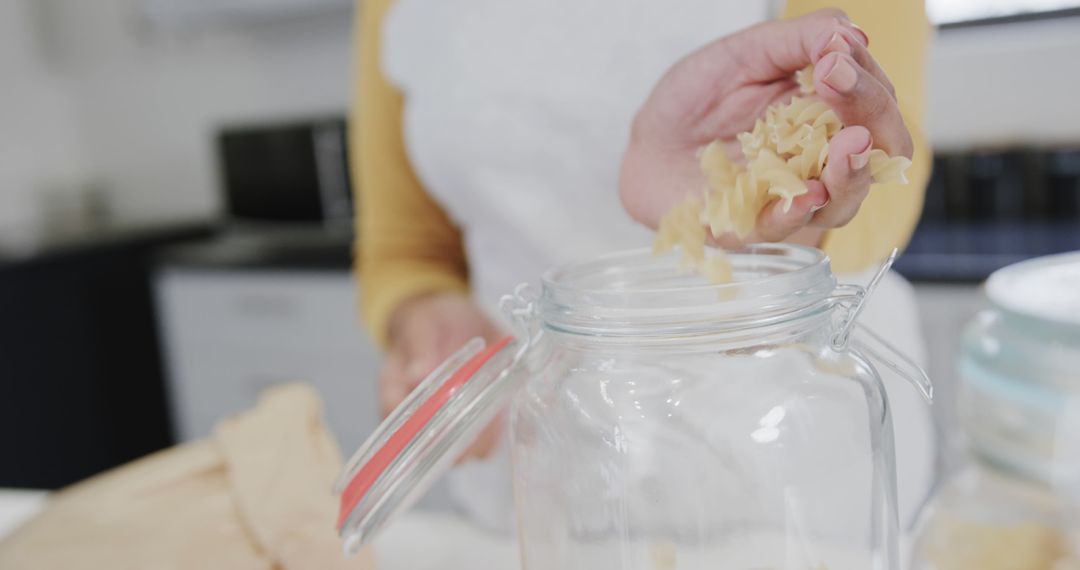 Woman Filling Jar with Pasta in Kitchen - Free Images, Stock Photos and Pictures on Pikwizard.com