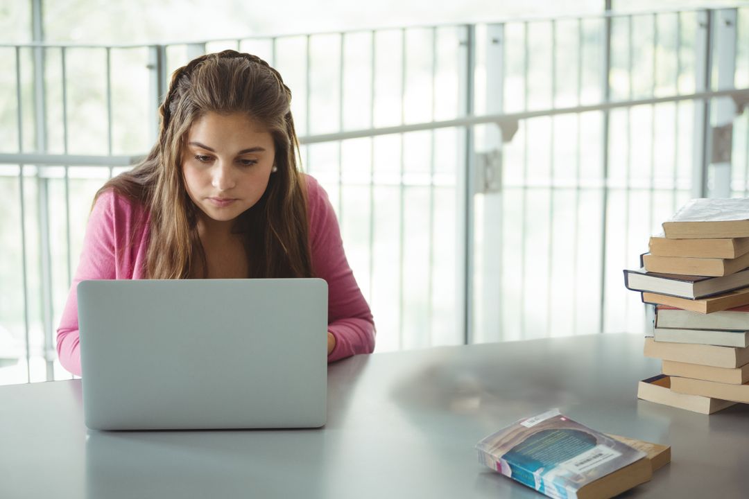 Focused Student Using Laptop in Bright Library for Study