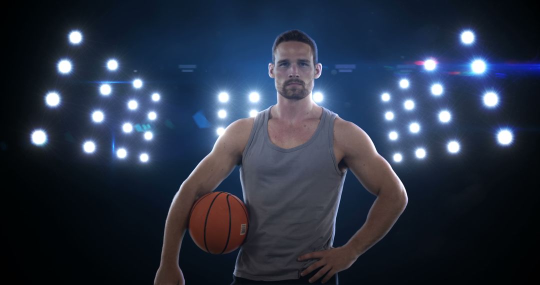 Confident Basketball Player Holding Ball in Stadium with Bright Lights - Free Images, Stock Photos and Pictures on Pikwizard.com