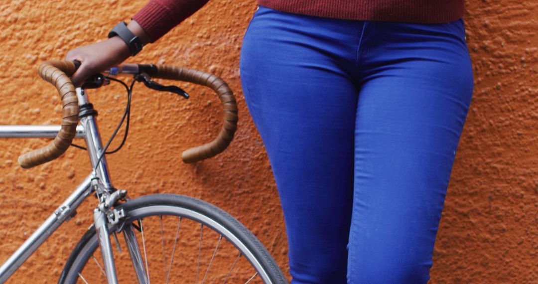 African American woman standing with bicycle against colorful wall - Free Images, Stock Photos and Pictures on Pikwizard.com