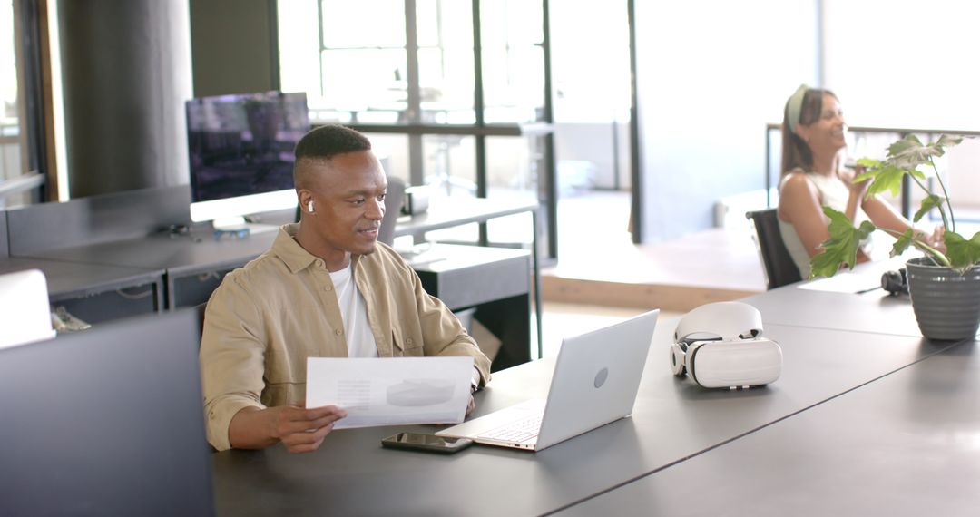 Smiling Businessman Reviewing Documents with Technology in Modern Office