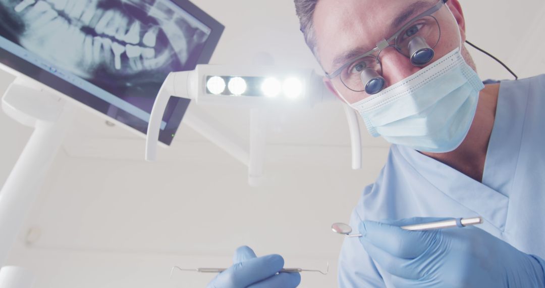 Dentist Examining Patient with Dental Instruments and X-ray Display - Free Images, Stock Photos and Pictures on Pikwizard.com